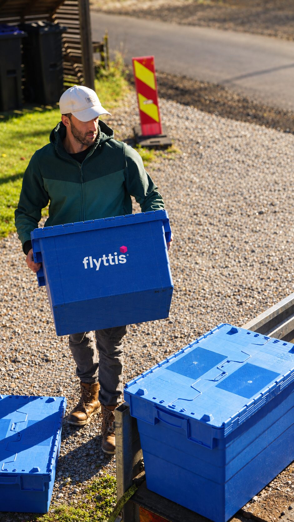 Flyttis-medarbeider bærer en blå flyttekasse med Flyttis-logo til hengeren